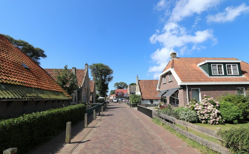 A cobblestone street lined with houses and hedges